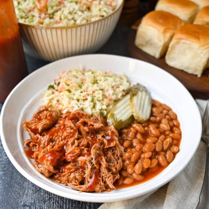 a BBQ bowl with pulled pork, beans, slaw, and pickles