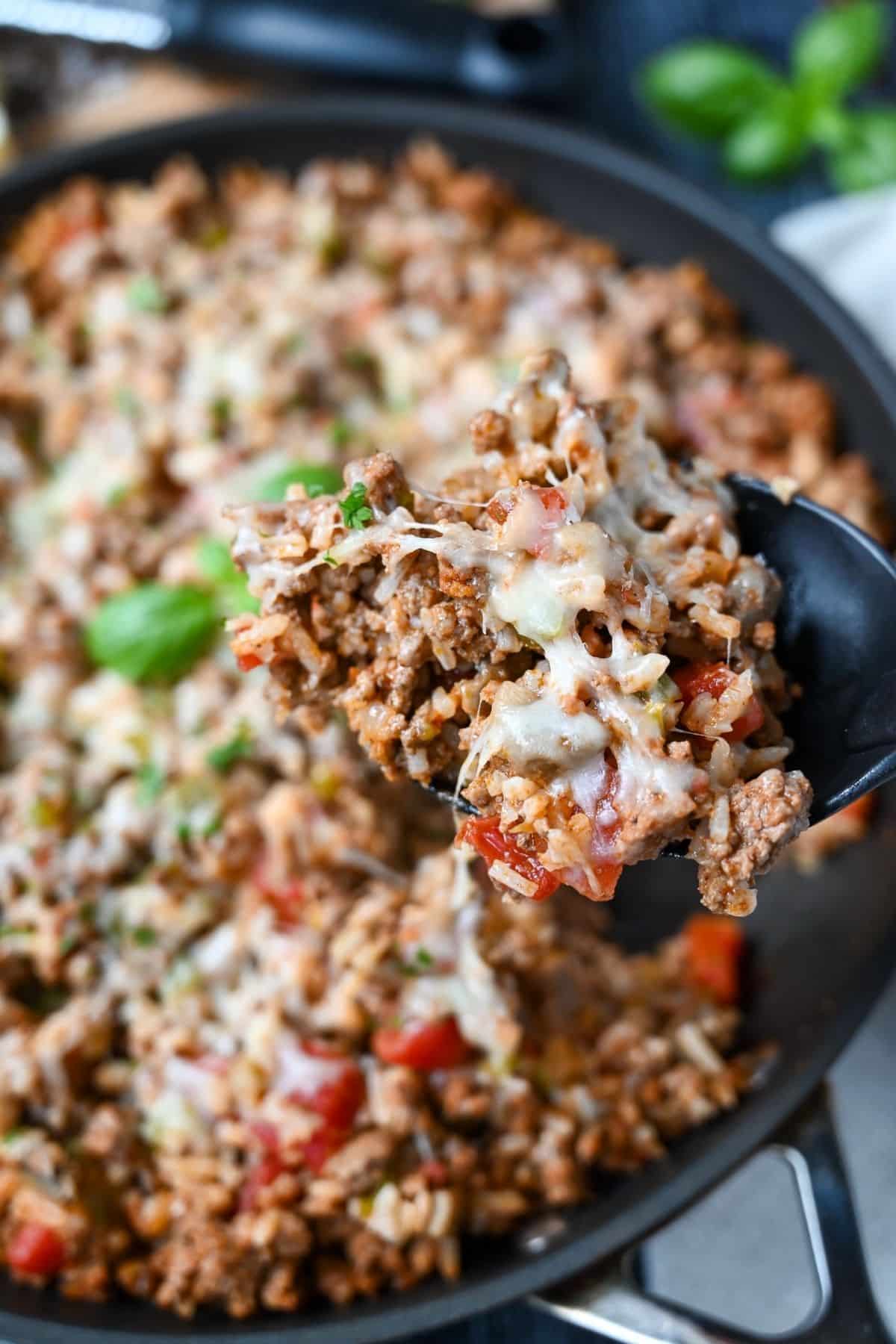 holding up a cheesy spoonful of Italian ground beef skillet 