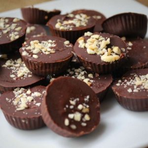 homemade chocolates topped with crushed hazelnuts stacked on a plate