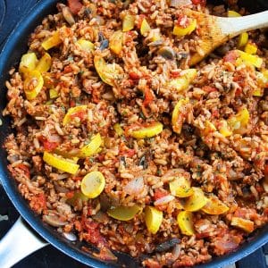 close up of a ground pork skillet meal with yellow squash, rice, tomatoes, and seasonings