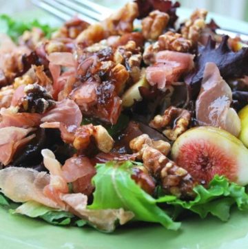 close-up photo of a mixed green salad with prosciutto ham, figs, and nuts