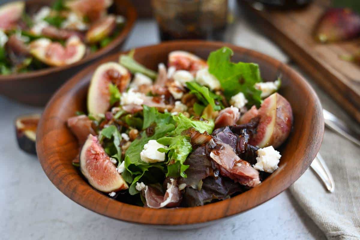 a served bowl of salad with prosciutto ham, nuts, gorgonzola, and figs