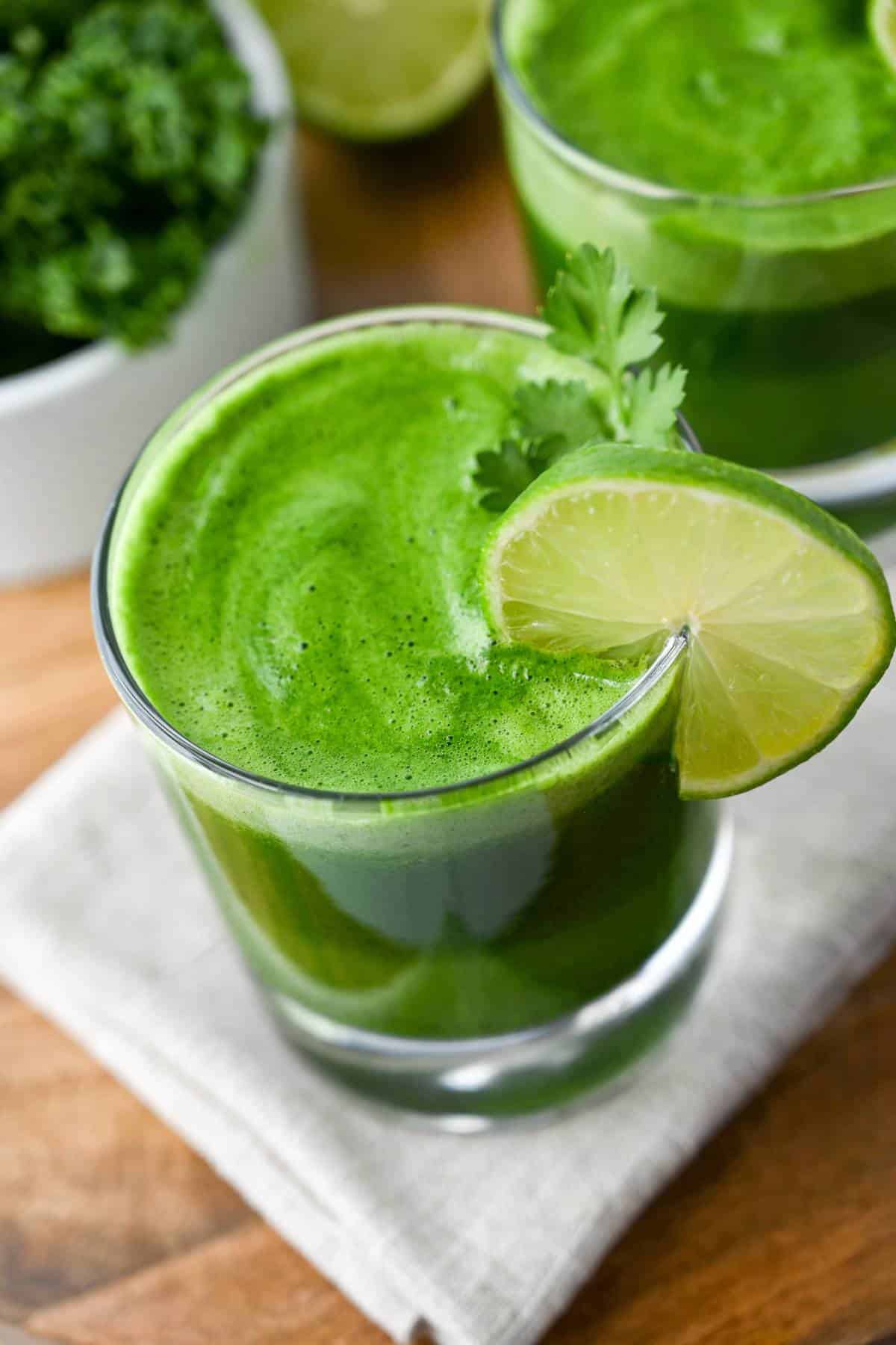 green juice in glasses with lime and a sprig of parsley