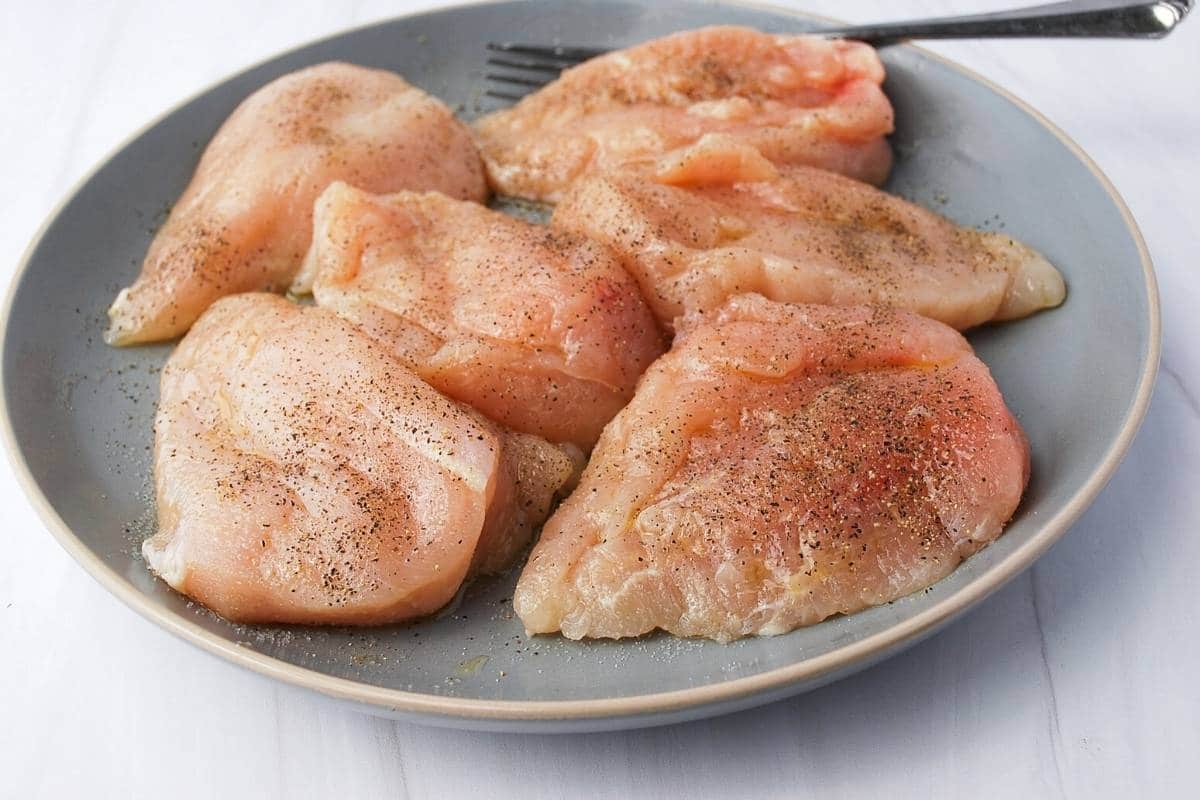 chicken breasts brushed with olive oil and seasoned with salt and pepper on a plate