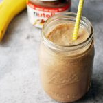 Nutella protein shake in a mason jar with banana and jar of Nutella in the background