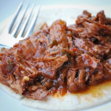 close up photo of shredded beef roast on a flour tortilla
