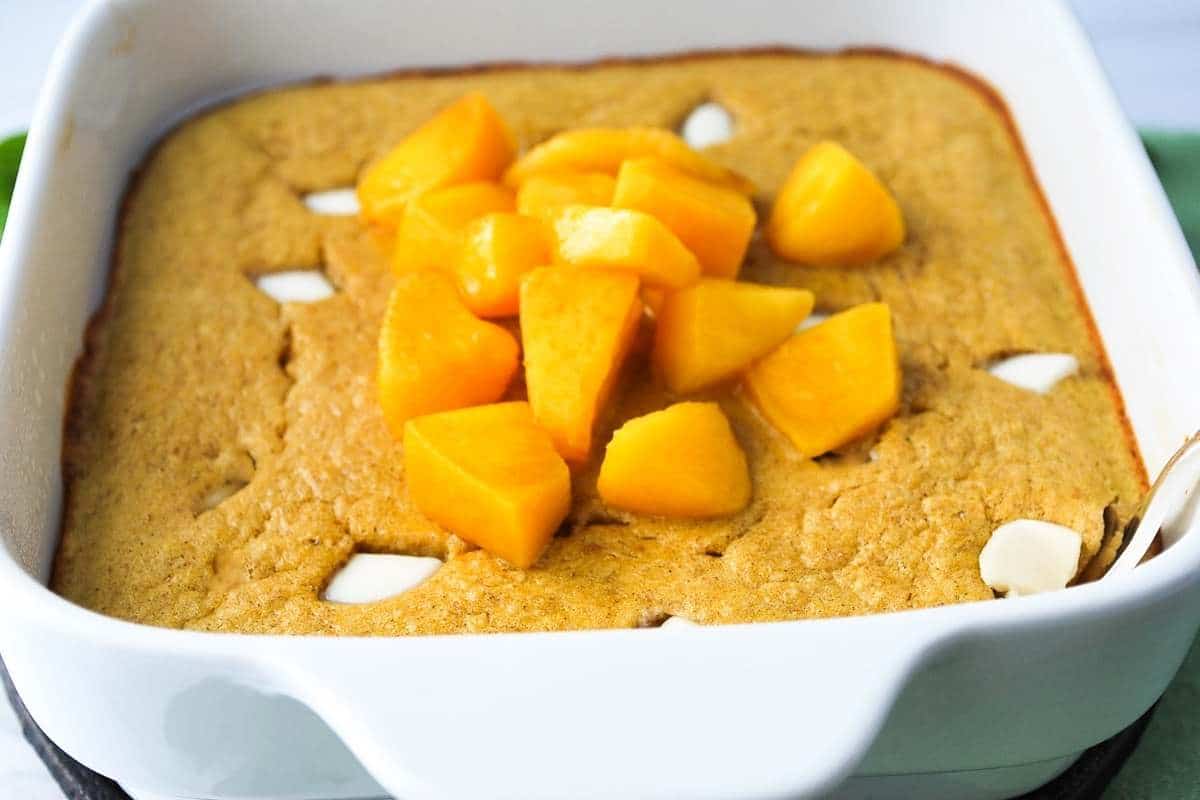 protein baked oatmeal with white chocolate chips fresh from the oven topped with peaches