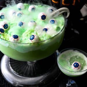 close up of smokey, bubbly witches Halloween punch with floating eyeballs and lime sherbert
