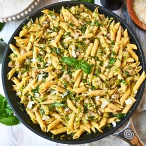 a skillet with zucchini pasta with sausage and fresh basil