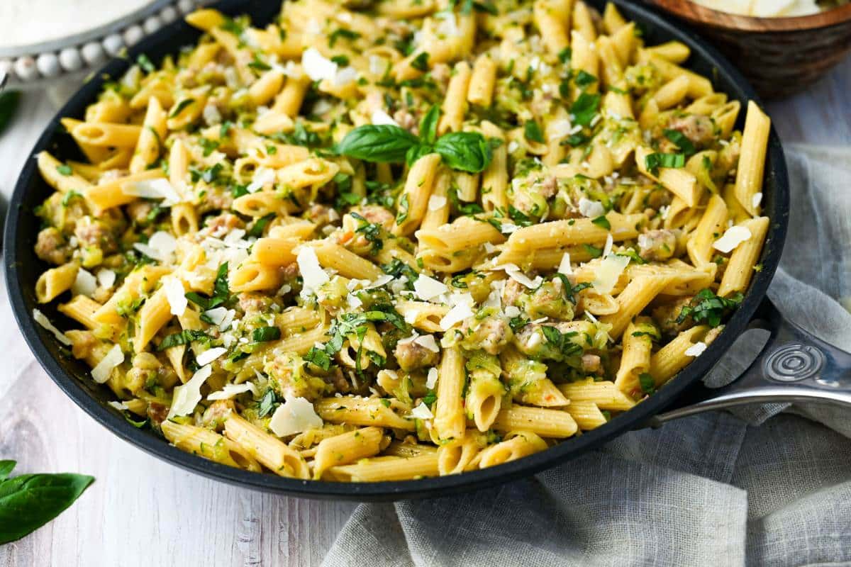 side view of a cooked zucchini pasta skillet with a sprig of fresh basil on top