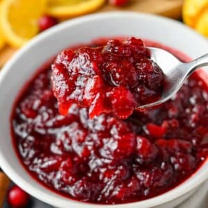 a spoonful of whole berry cranberry sauce over a serving bowl of cranberry sauce