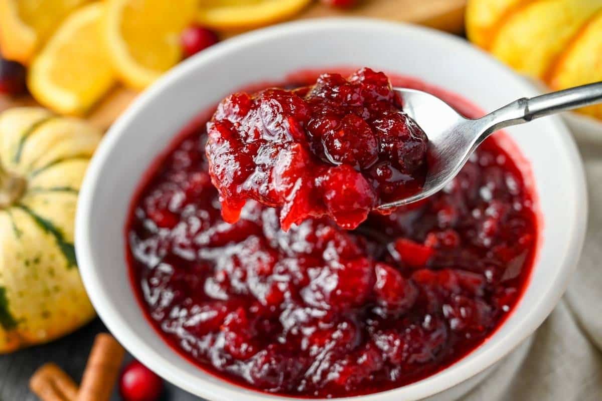 holding up a spoonful of homemade cranberry sauce in a white bowl