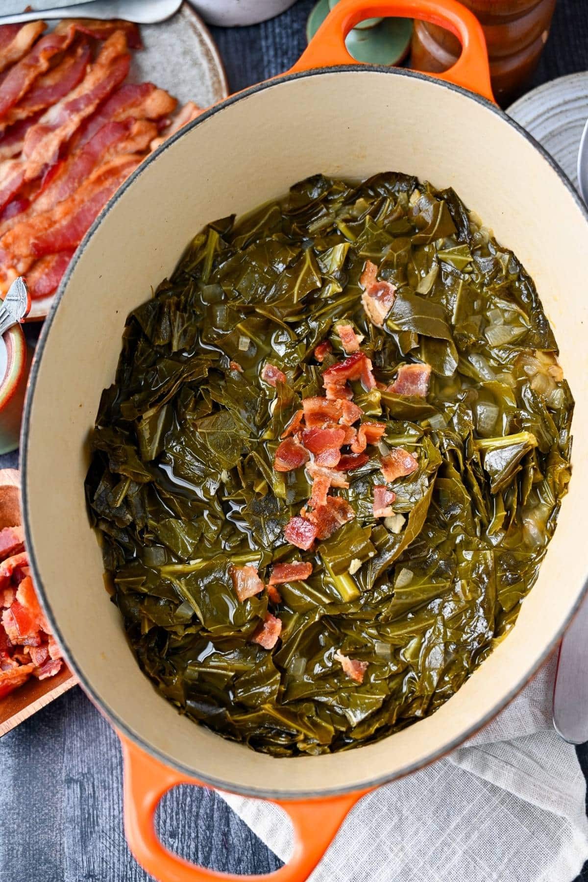 a pot of braised collard greens with crumbled bacon on top