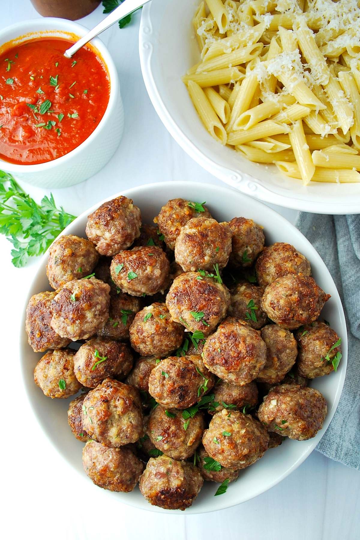 overhead photo of meatballs in a bowl with pasta and sauce on the side