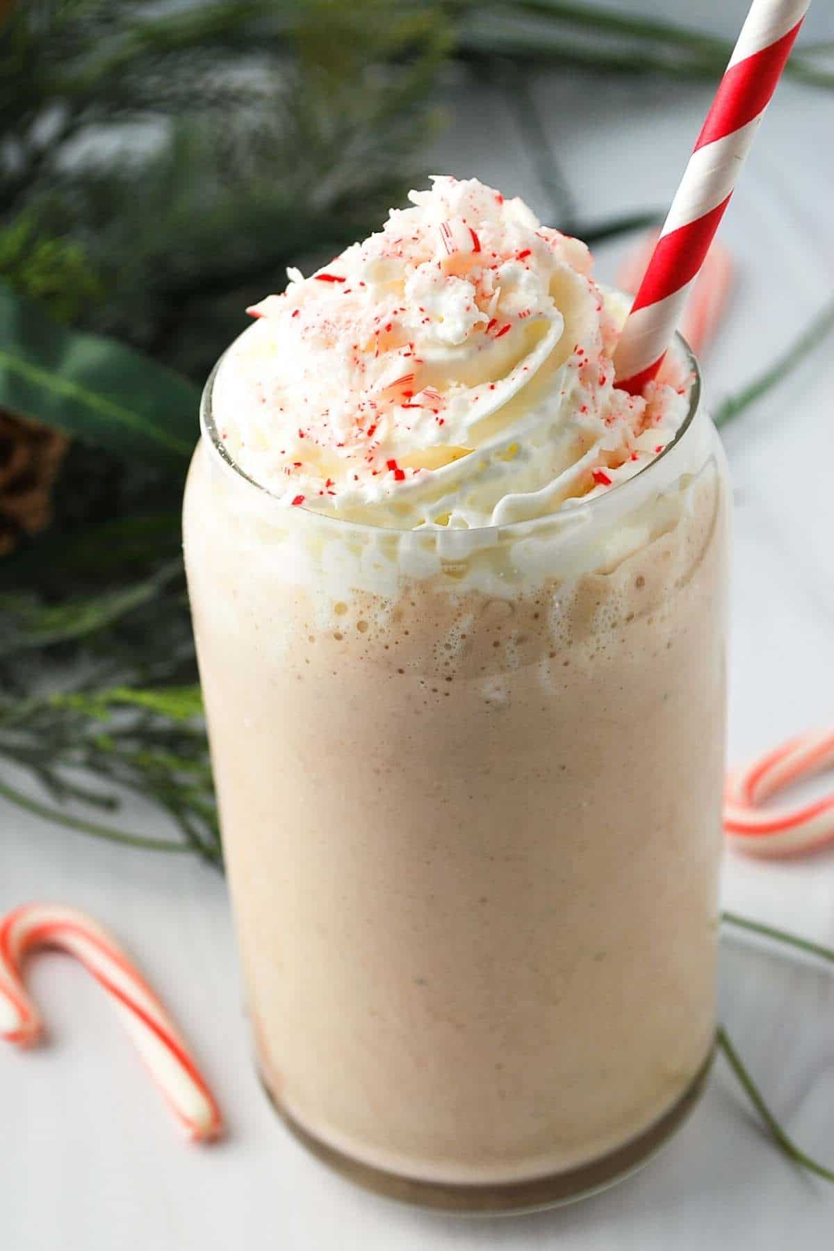 A peppermint protein shake in a glass with whipped cream and crushed candy canes