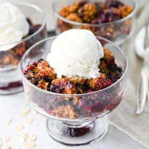 a dish of berry crisp topped with a scoop of vanilla ice cream
