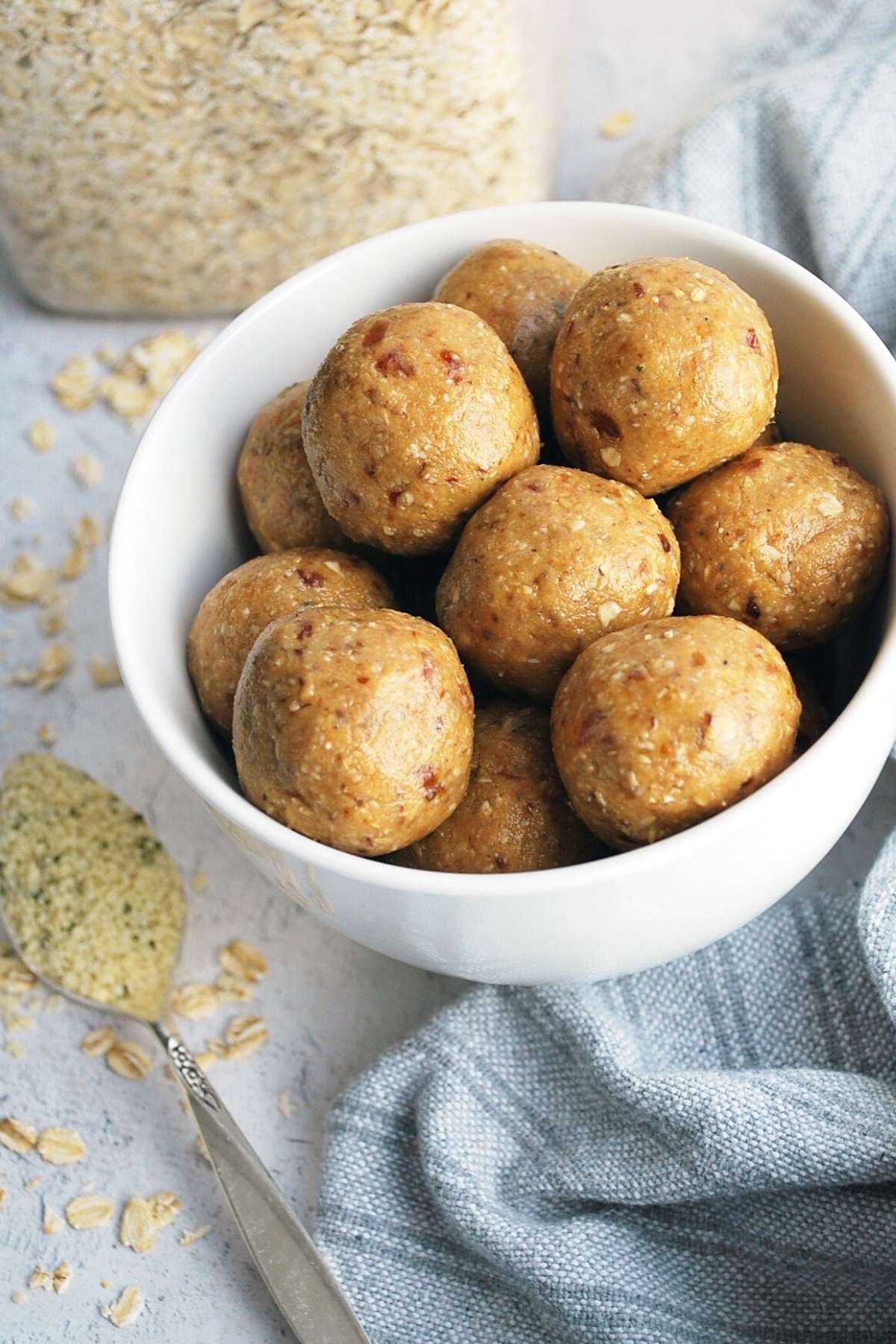 peanut butter protein balls in a white bowl with a jar of oats in the background