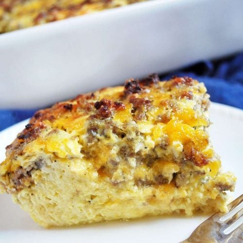 Overnight breakfast casserole with sausage and egg sliced on a plate with a fork next to it