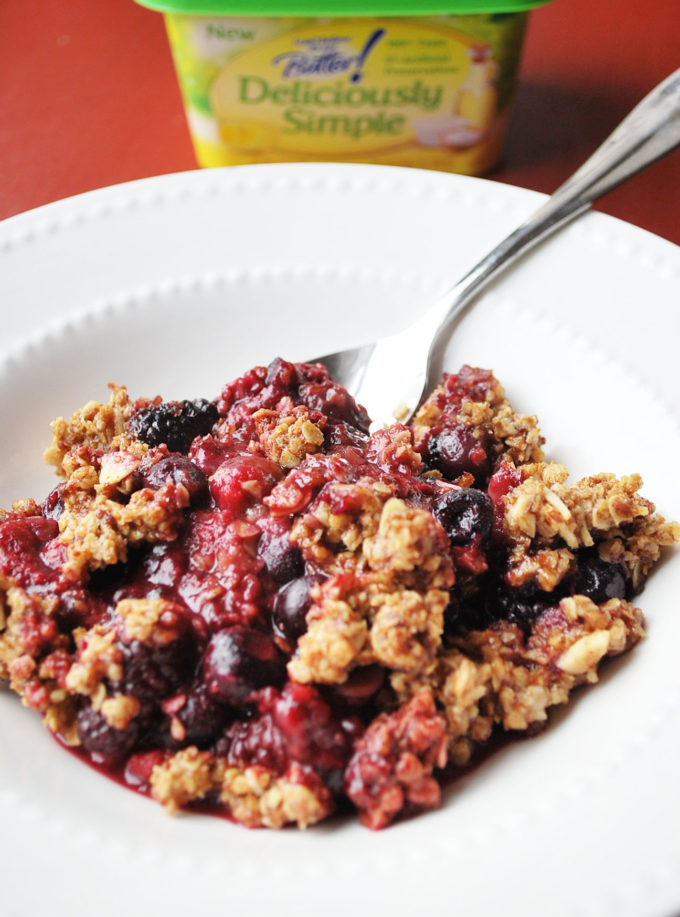Berry crumble in a white bowl with a spoon