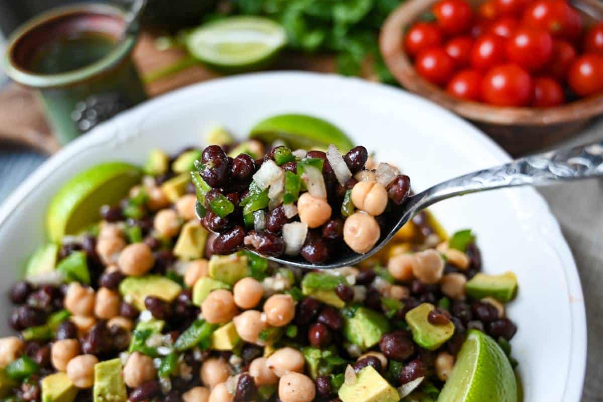 a spoonful of salad with black beans and chickpeas in a lime dressing