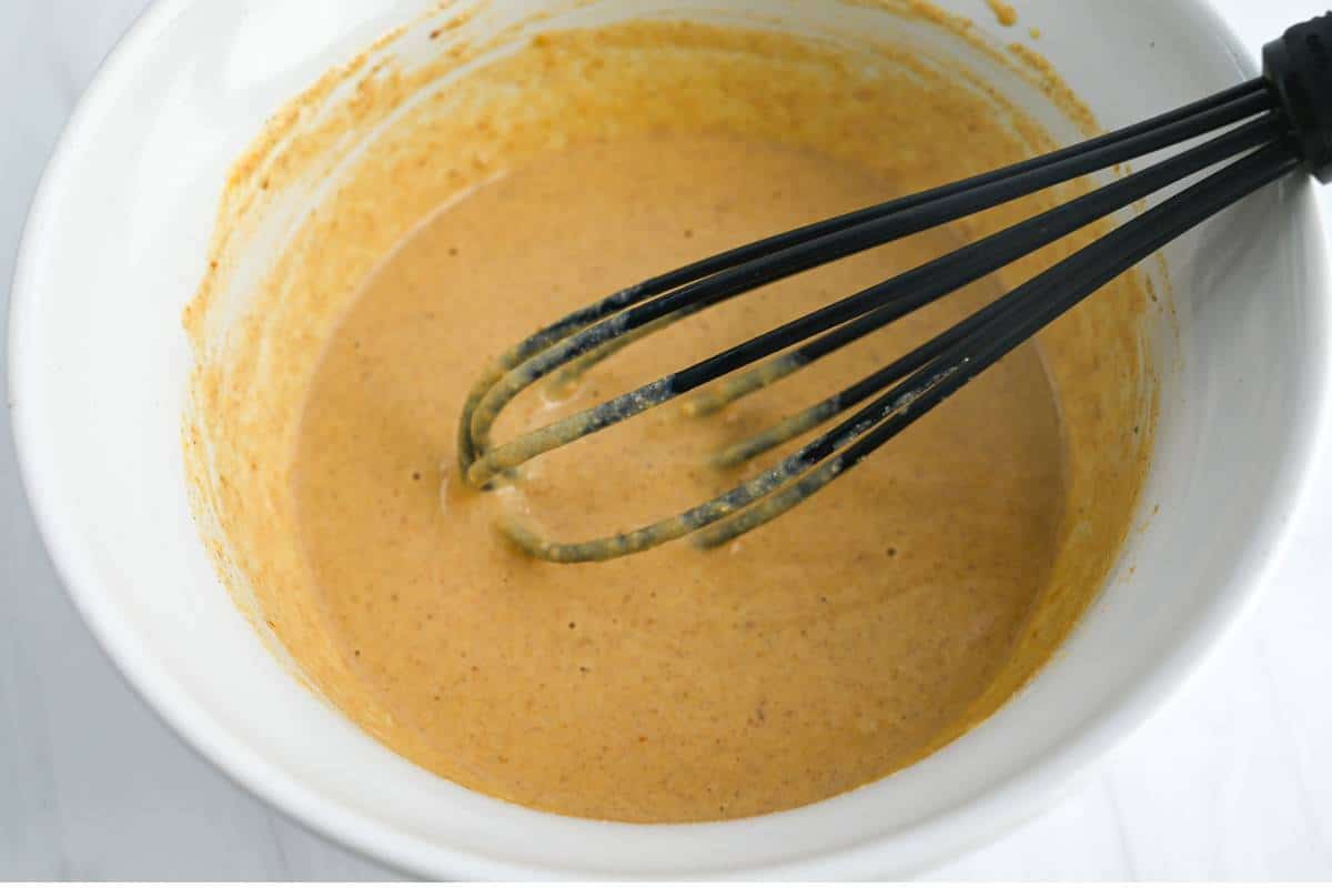 pumpkin pancake batter mixed in a bowl with a black whisk