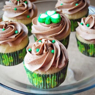 Cupcakes on a platter in St. Patrick's Day themed cupcake liners and green candy sprinkles on top