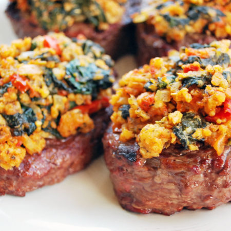 Four grilled steaks topped with a Mediterranean topping blend of spinach, feta and sun-dried tomato pesto