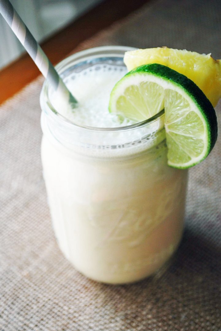 tropical protein shake in a mason jar with straw and fruit