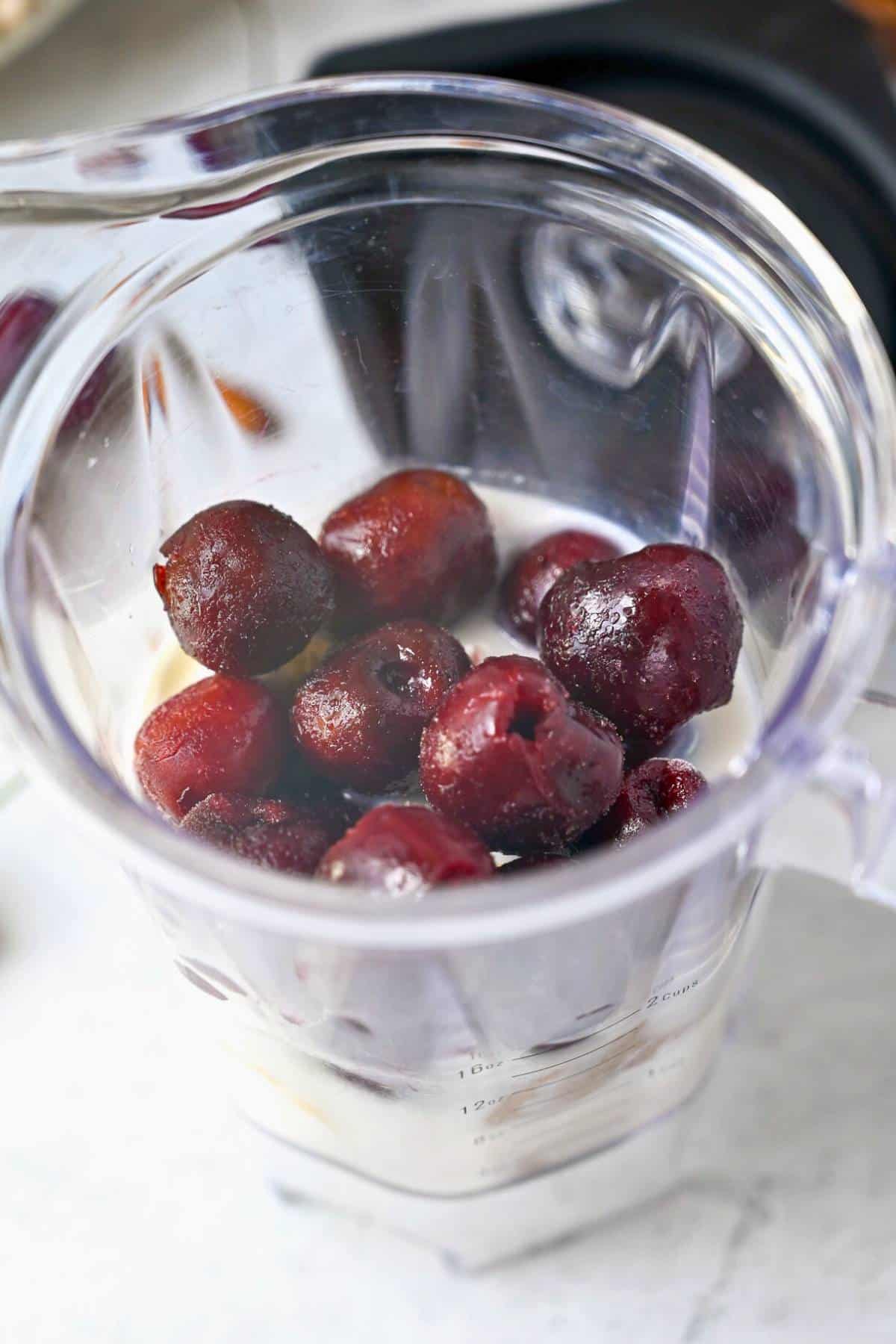 ingredients for a cherry almond smoothie in a blender jar