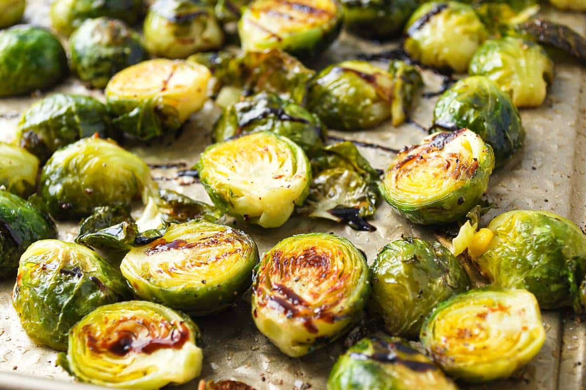 caramelized brussels sprouts close up on a baking sheet drizzled with balsamic