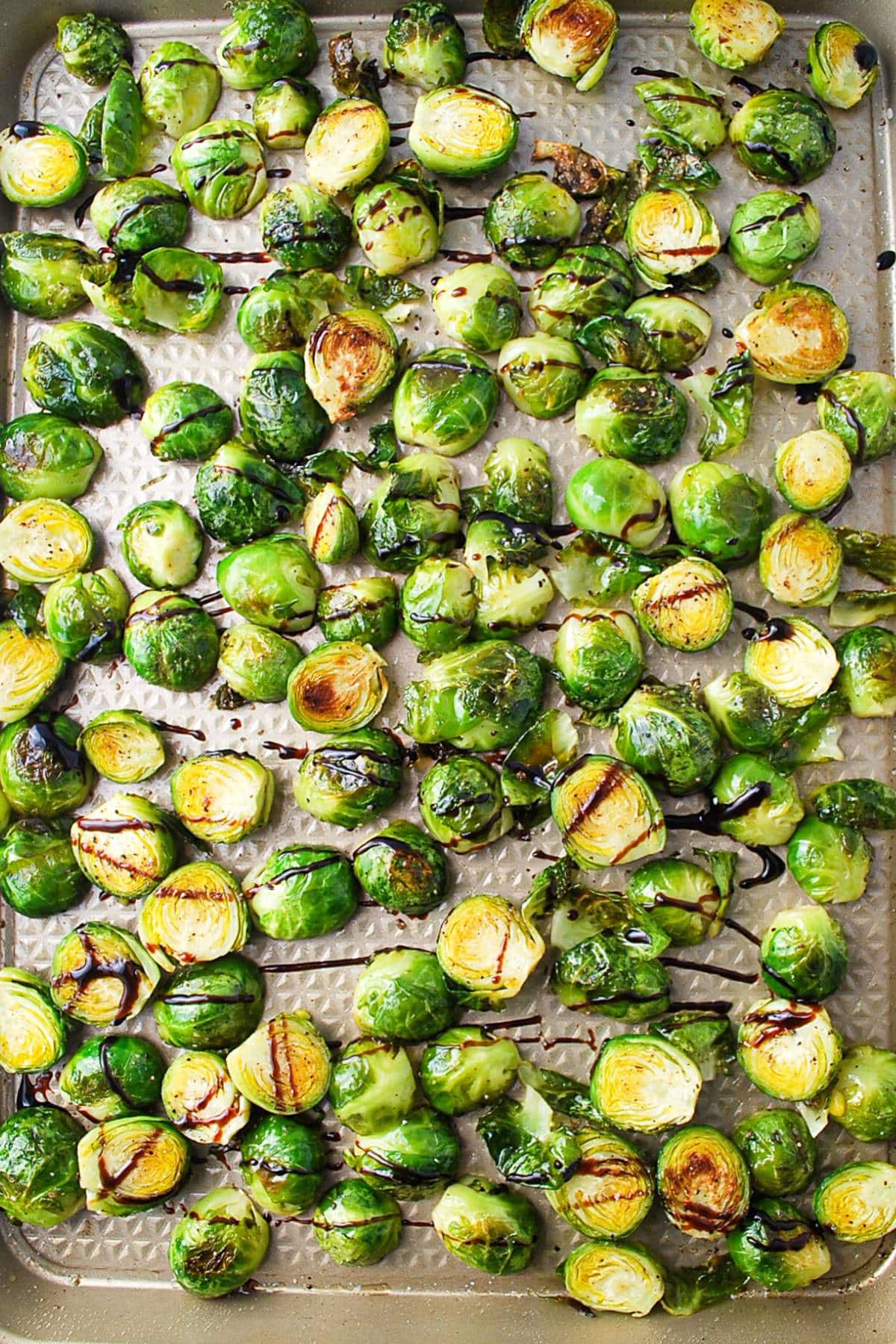 brussels sprouts drizzled with balsamic vinegar on a baking sheet