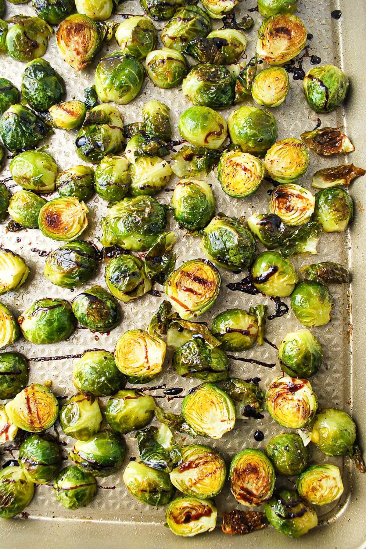 caramelized brussels with balsamic drizzled all over on a baking sheet