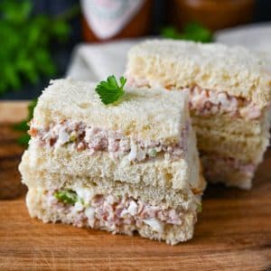 stacked ham salad sandwiches on a cutting board