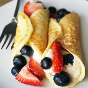 2 berry stuffed crepes on a plate with fork