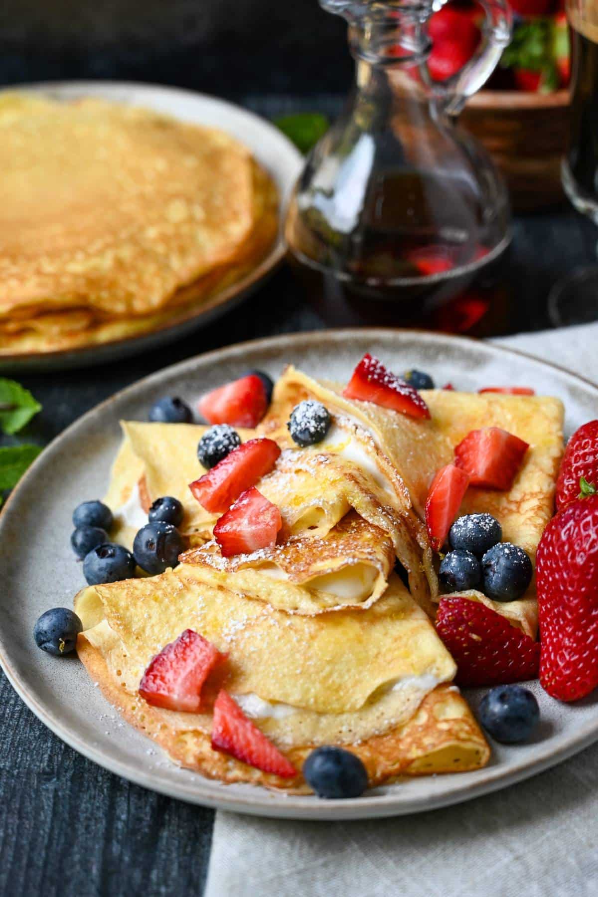 a plate of crepes with powdered sugar and berries on top