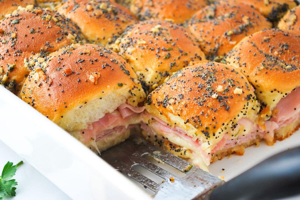 baked ham sliders with swiss cheese and a poppy seed butter glaze in a casserole dish