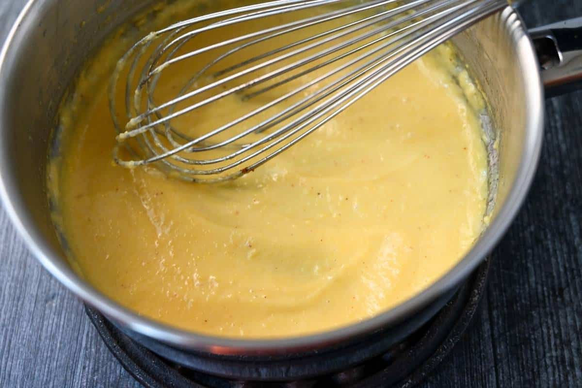 hollandaise sauce in a saucepan with a whisk