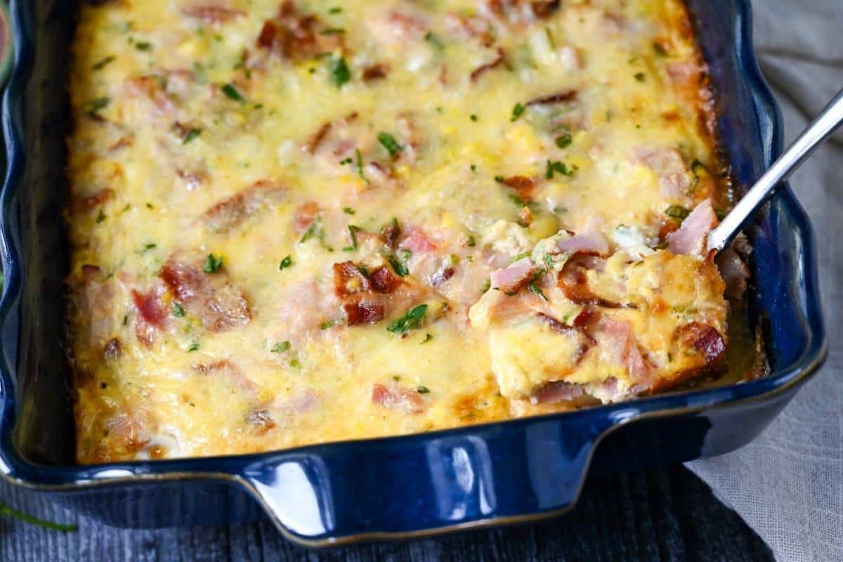 a spoon dipped into a pan of breakfast casserole ready to serve