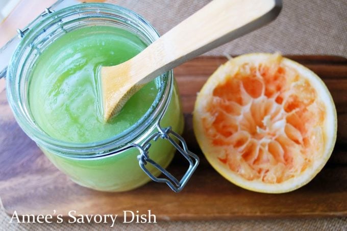 Jar of sugar scrub with a spoon and a sliced grapefruit