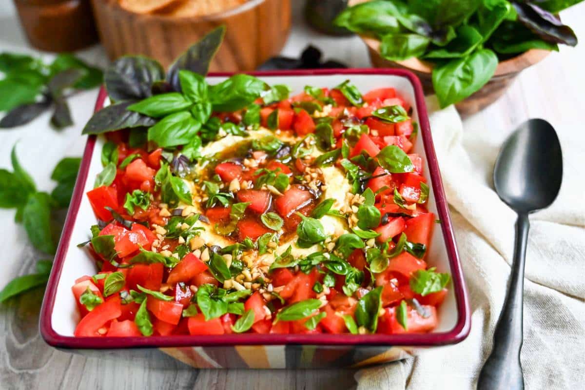 caprese dip in a bowl with a napkin and spoon next to it