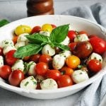 close up of caprese salad in a bowl with fresh basil