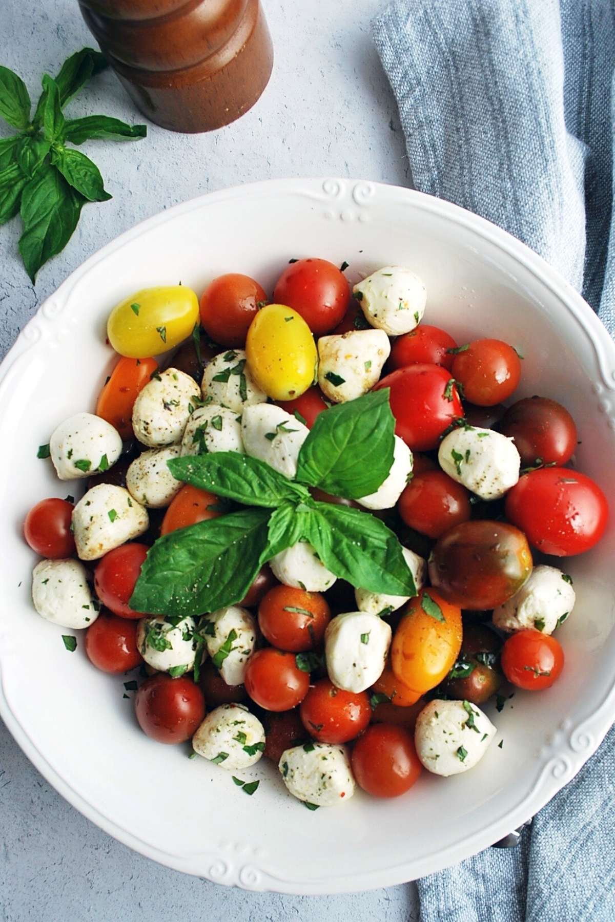 overhead photo of a bowl of caprese salad with fresh basil on top
