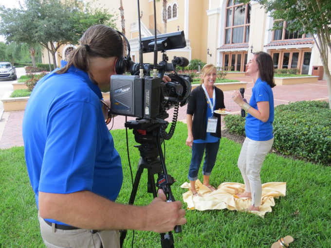 A couple of people that are standing in the grass doing an interview