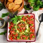 a cheese ball with tomatoes and basil in a bowl