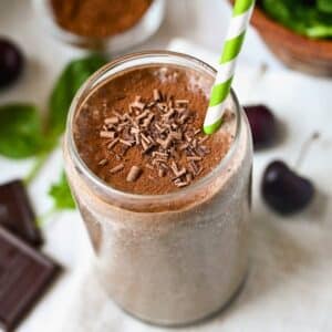 looking down at a chocolate cherry smoothie in a glass with chocolate shavings and a straw