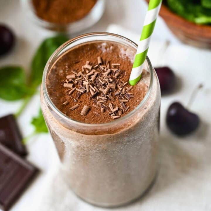 looking down at a chocolate cherry smoothie in a glass with chocolate shavings and a straw