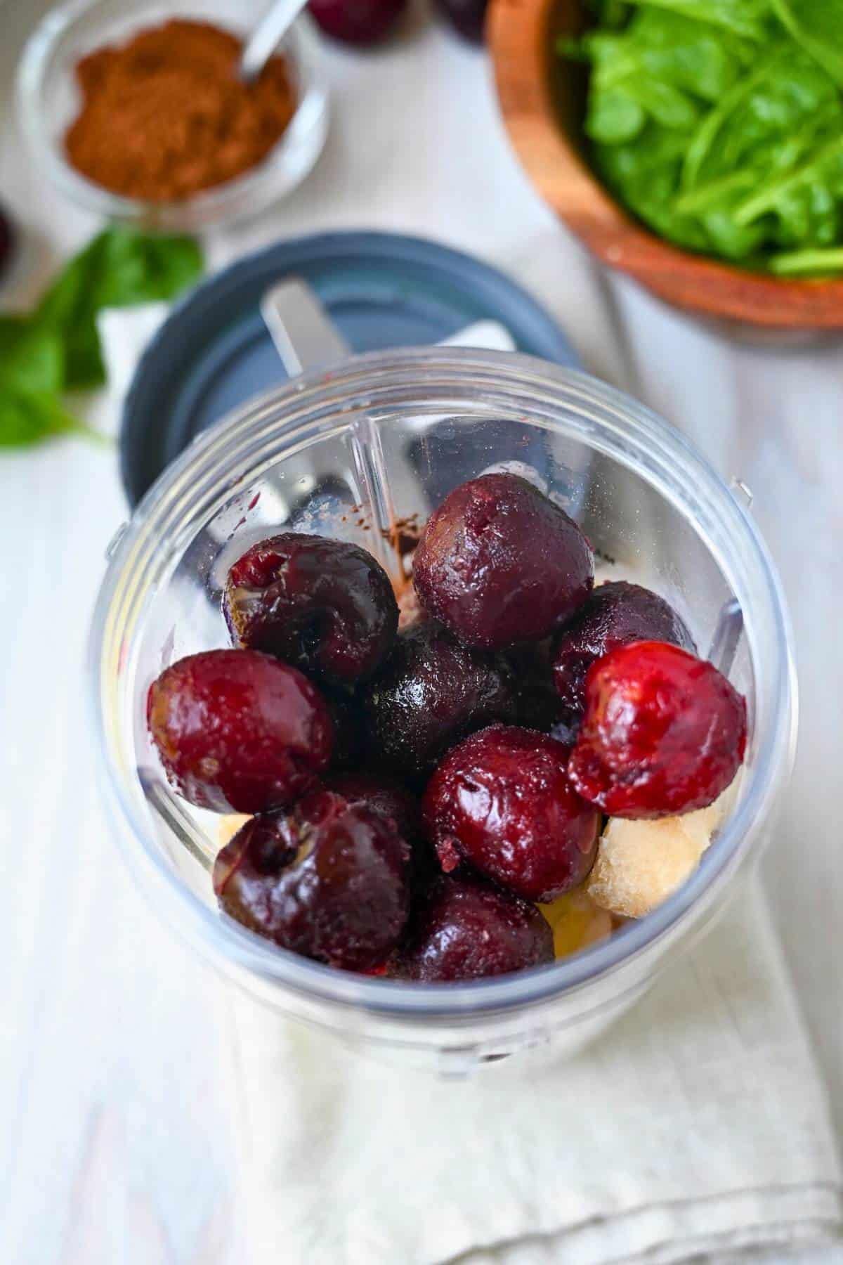 frozen cherries and smoothie ingredients in a blender jar