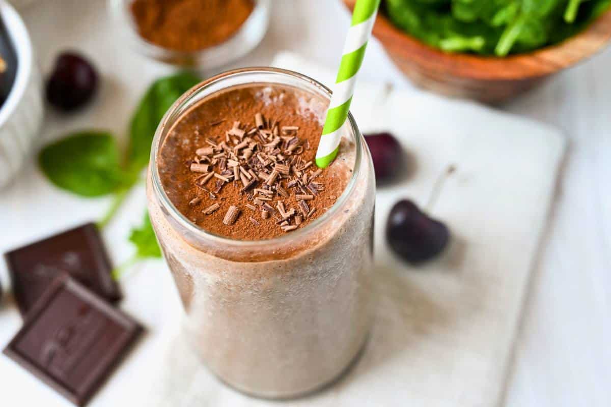 chocolate smoothie with bars of chocolate, cherries, and  baby spinach around it