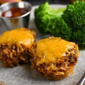 two mini BBQ meatloaves on a plate with cheese, BBQ sauce and broccoli