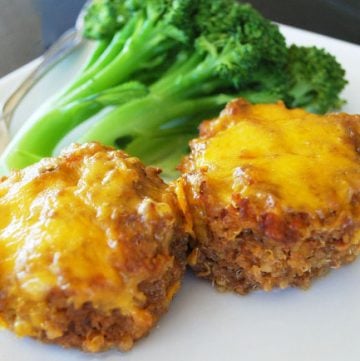 two barbecue meatloaves topped with cheese on a plate with broccoli